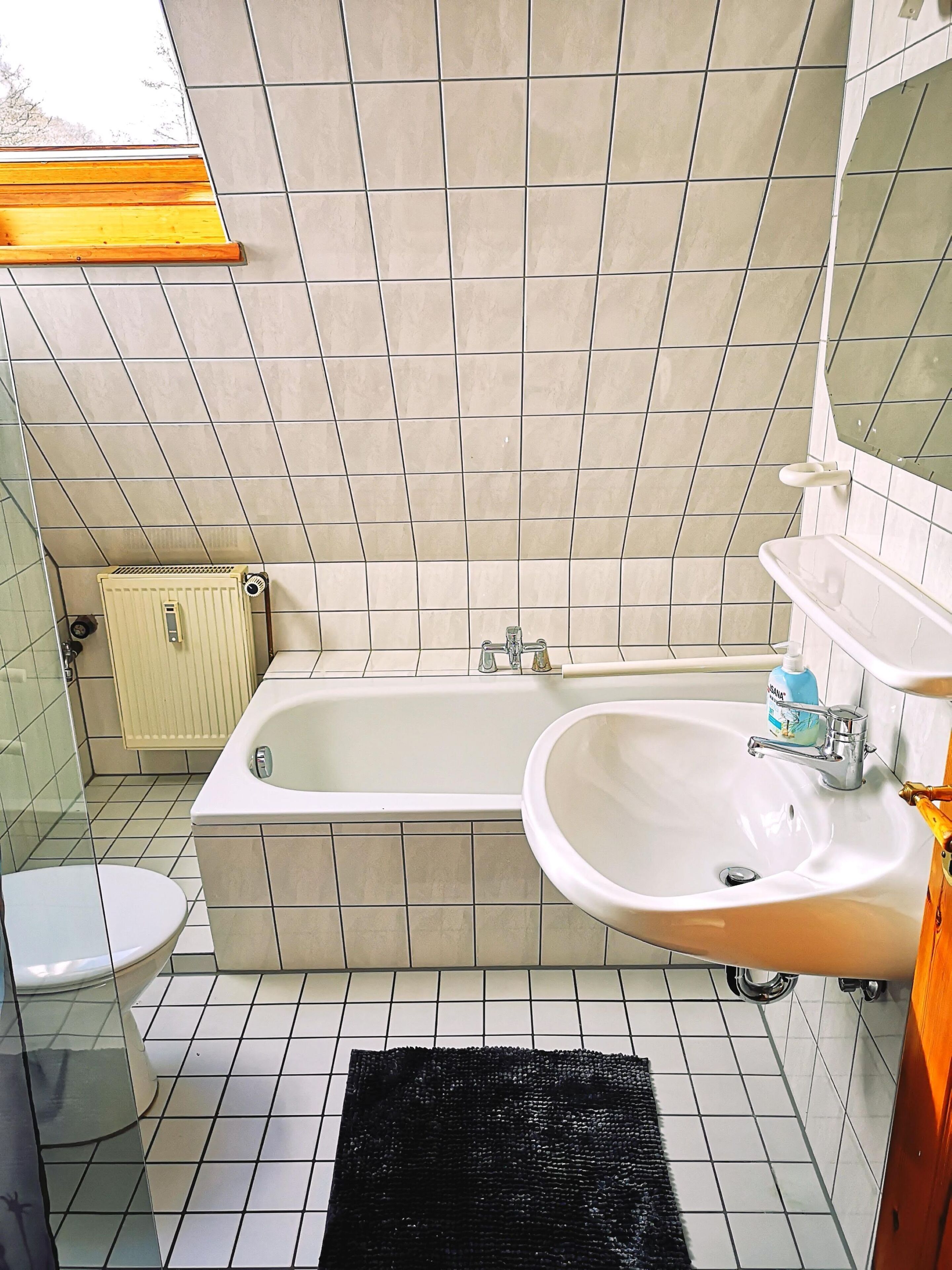 Een badkamer met een bad, wastafel, toilet en een raam.