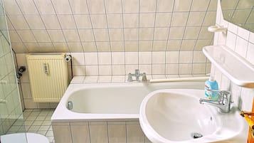 Een badkamer met een bad, wastafel, toilet en een raam.