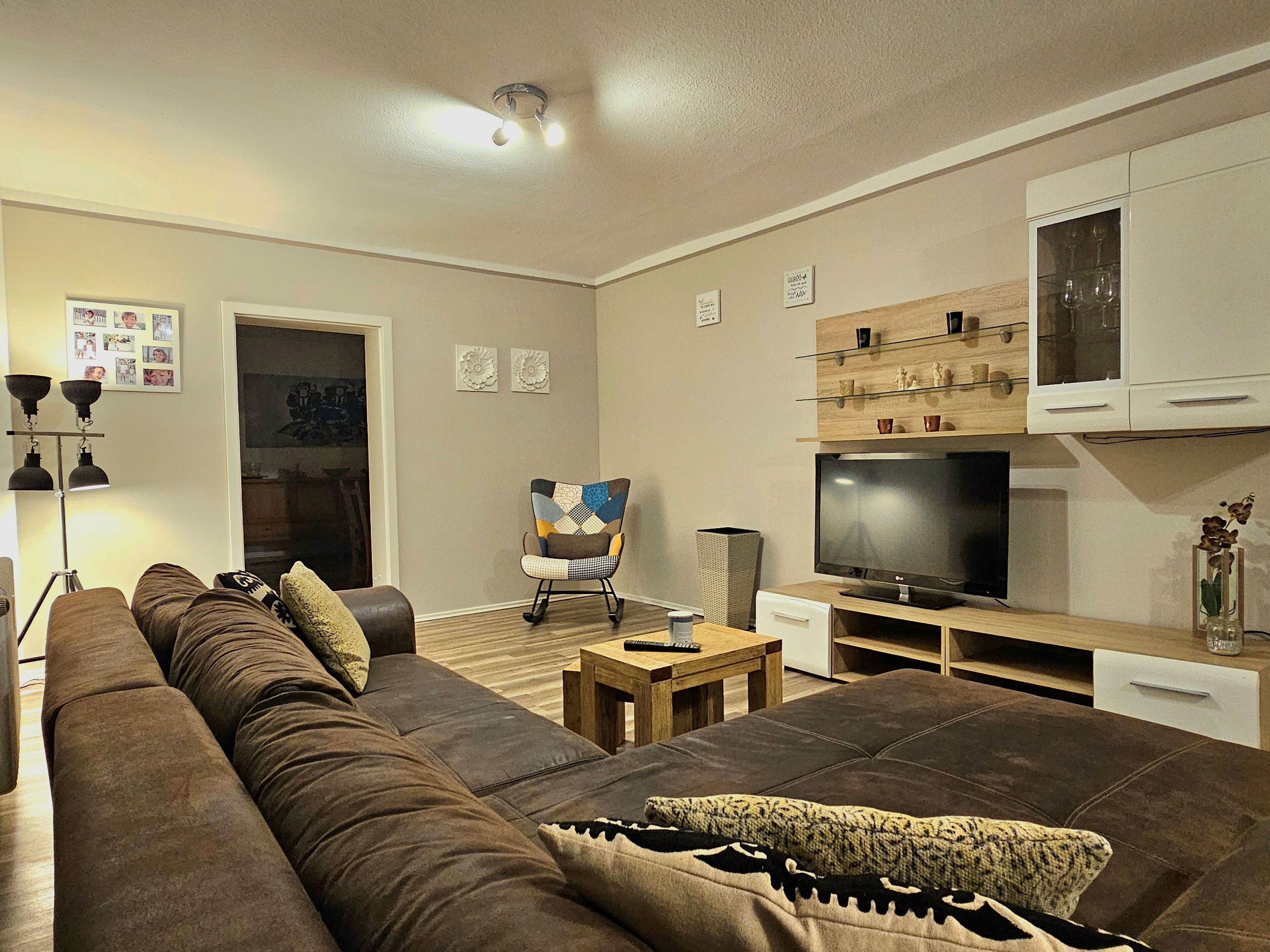 A living room with a brown sofa, a television, wooden cabinets, and a lamp.