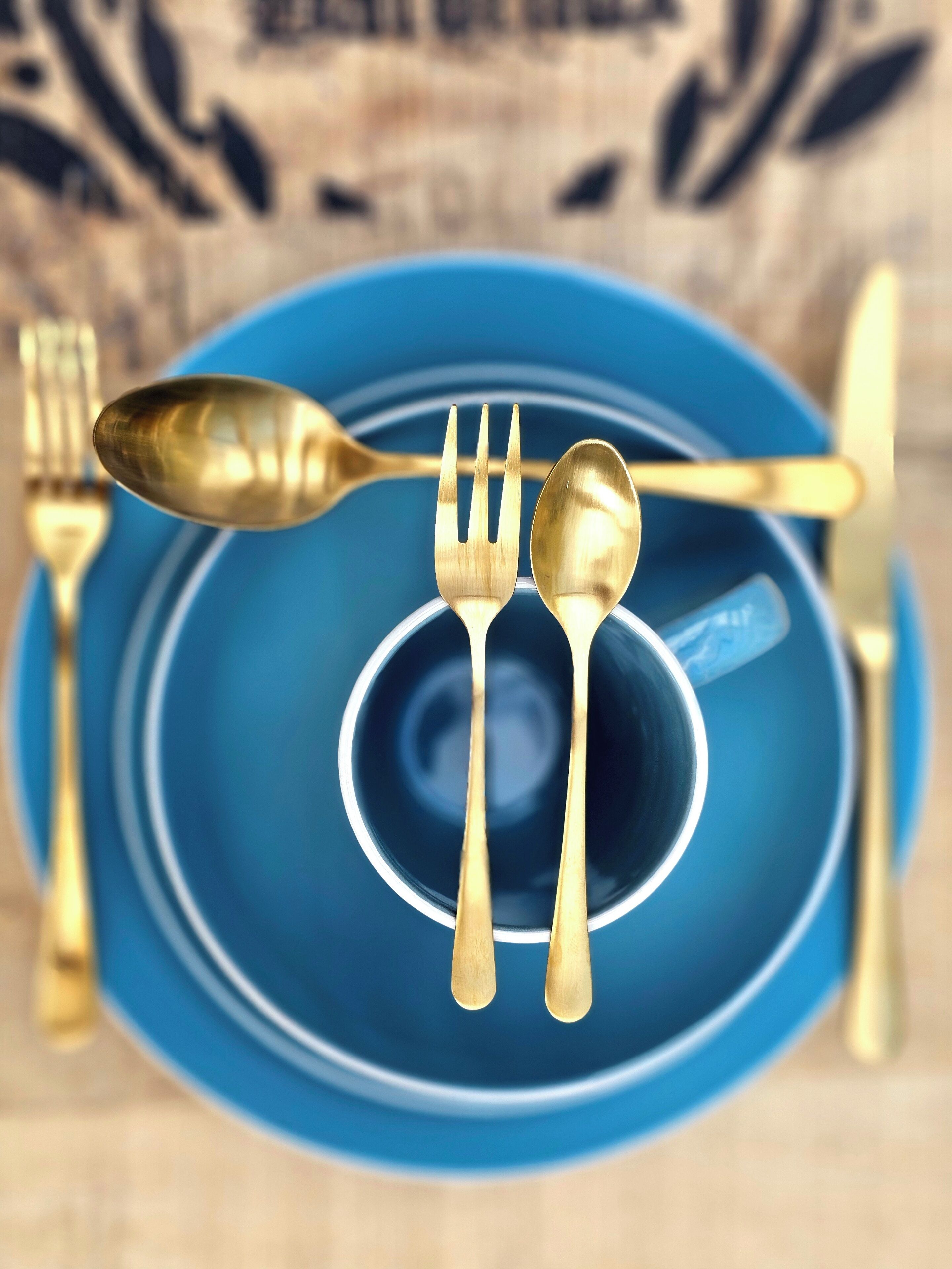 A blue plate with a spoon and fork on it.