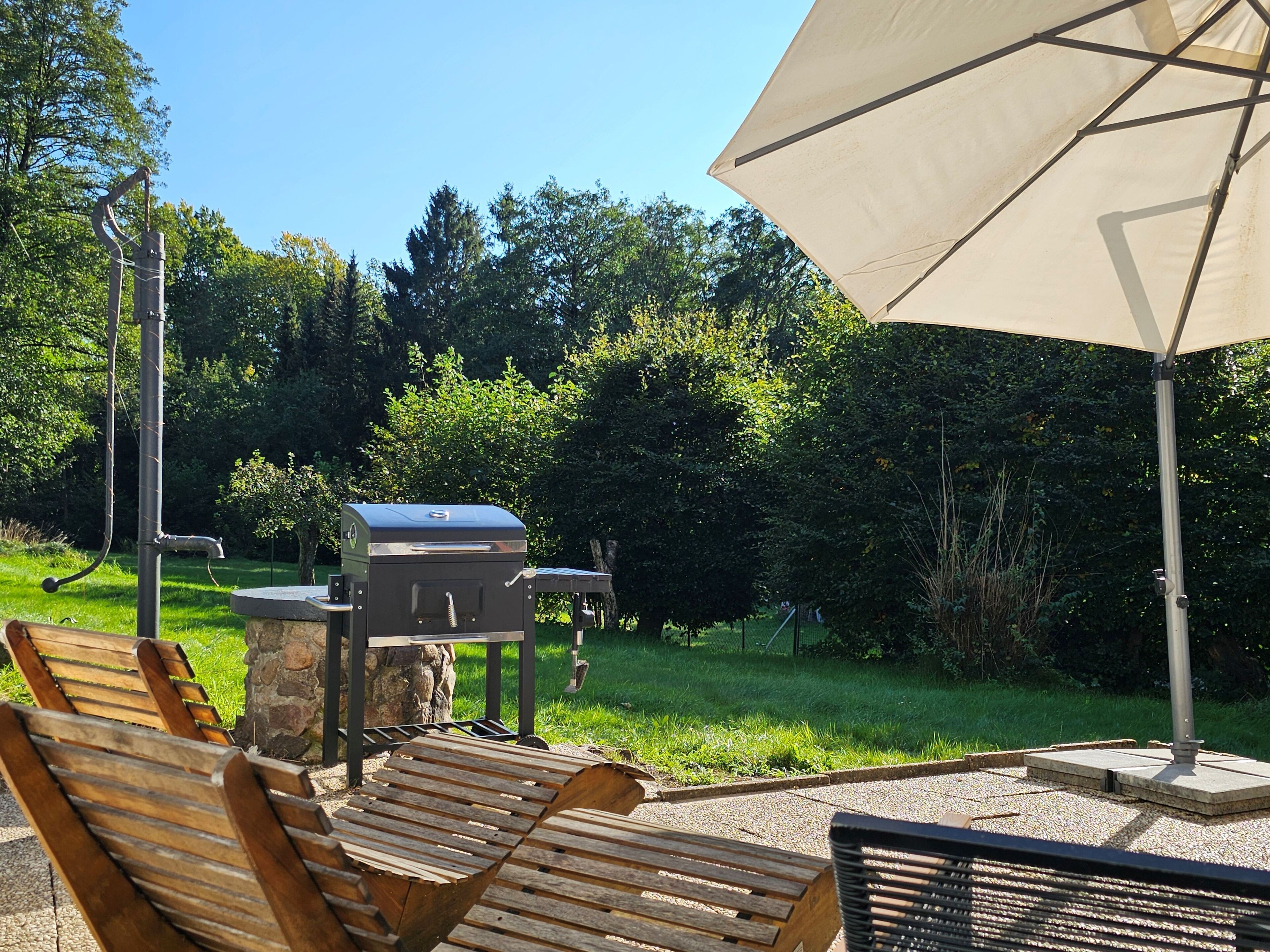 Zona d'estar a l'exterior amb bancs de fusta i una barbacoa.