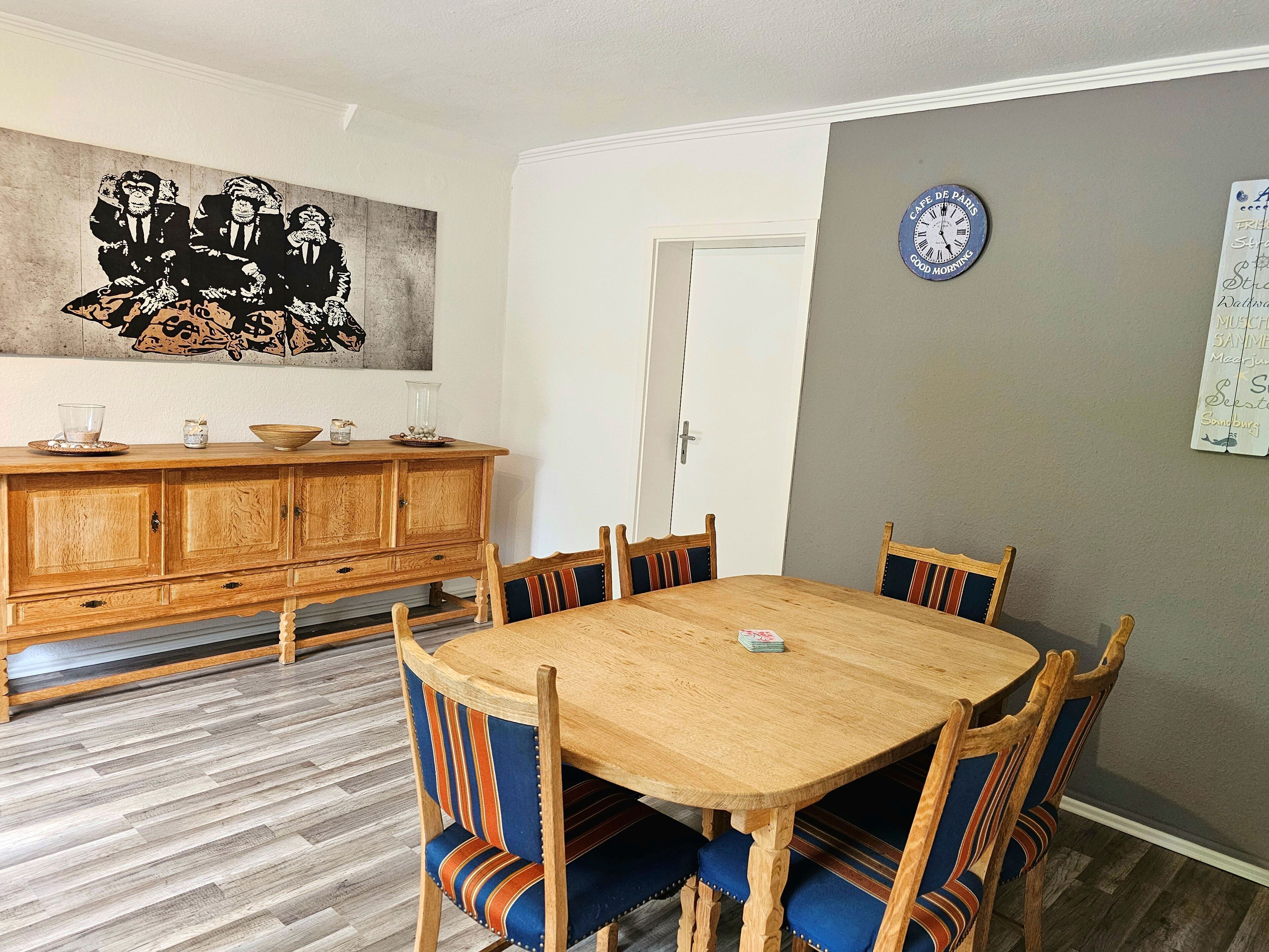 A dining area with a wooden table and chairs, a cabinet, and a wall clock.