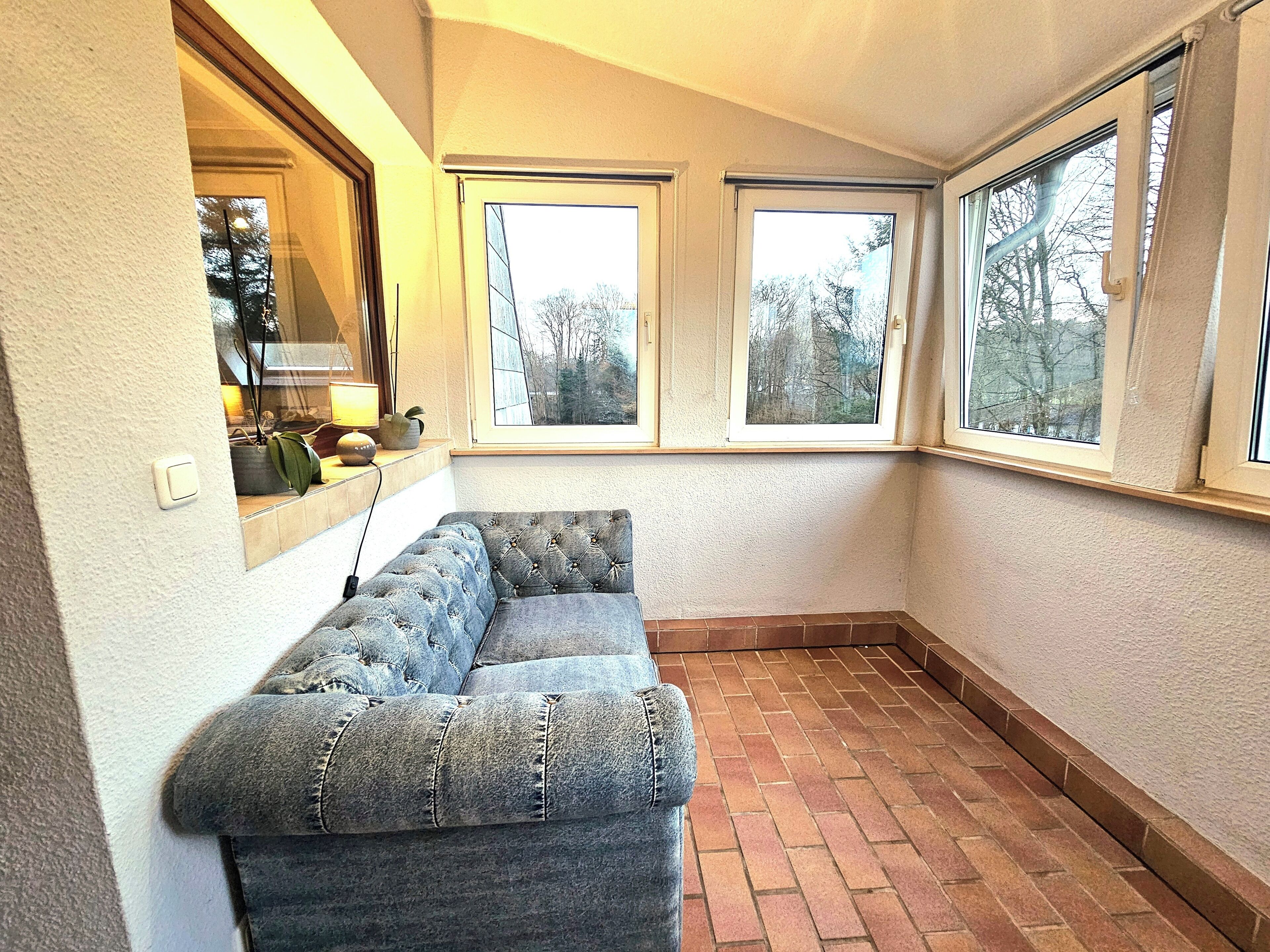 Ein Eckzimmer mit eingebauter Sitzbank, großen Fenstern und Steinboden.