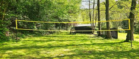 A fenced area with a net, surrounded by trees and grass.