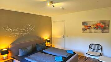 Un dormitorio con cama, lámparas de noche, una obra de arte en la pared y una silla.