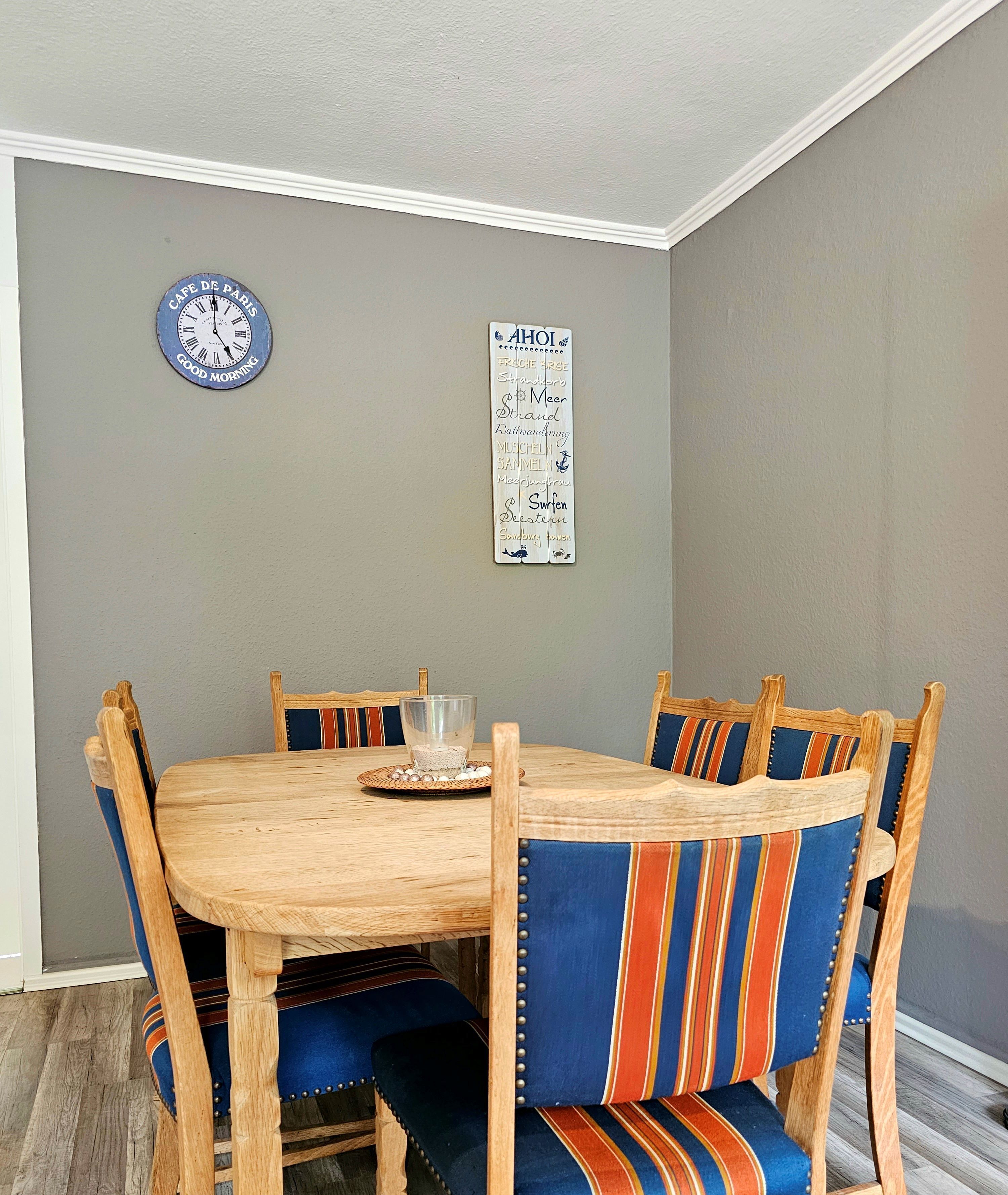 A dining area with a wooden table and striped upholstered chairs.