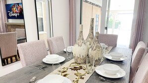 A dining area with a long table set for six, surrounded by upholstered chairs. - Family friendly home by Disneyland Universal DTLA SGV Pasadena Arcadia (San Gabriel)