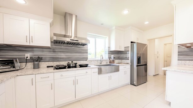 A modern kitchen with white cabinets, stainless steel appliances, and a marble countertop. - Family friendly home by Disneyland Universal DTLA SGV Pasadena Arcadia (San Gabriel)