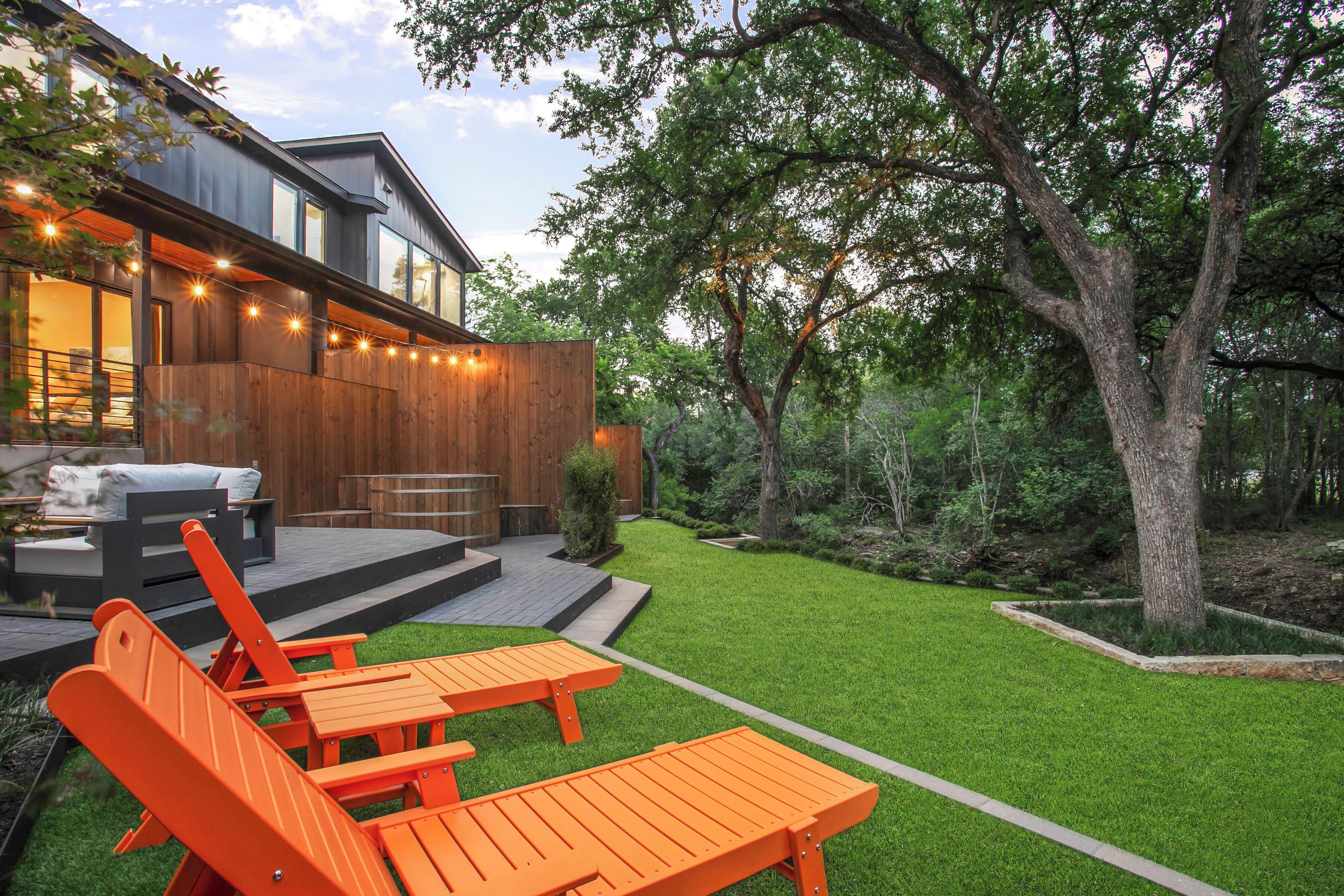 A modern house with a deck, outdoor seating, and a well-maintained lawn.