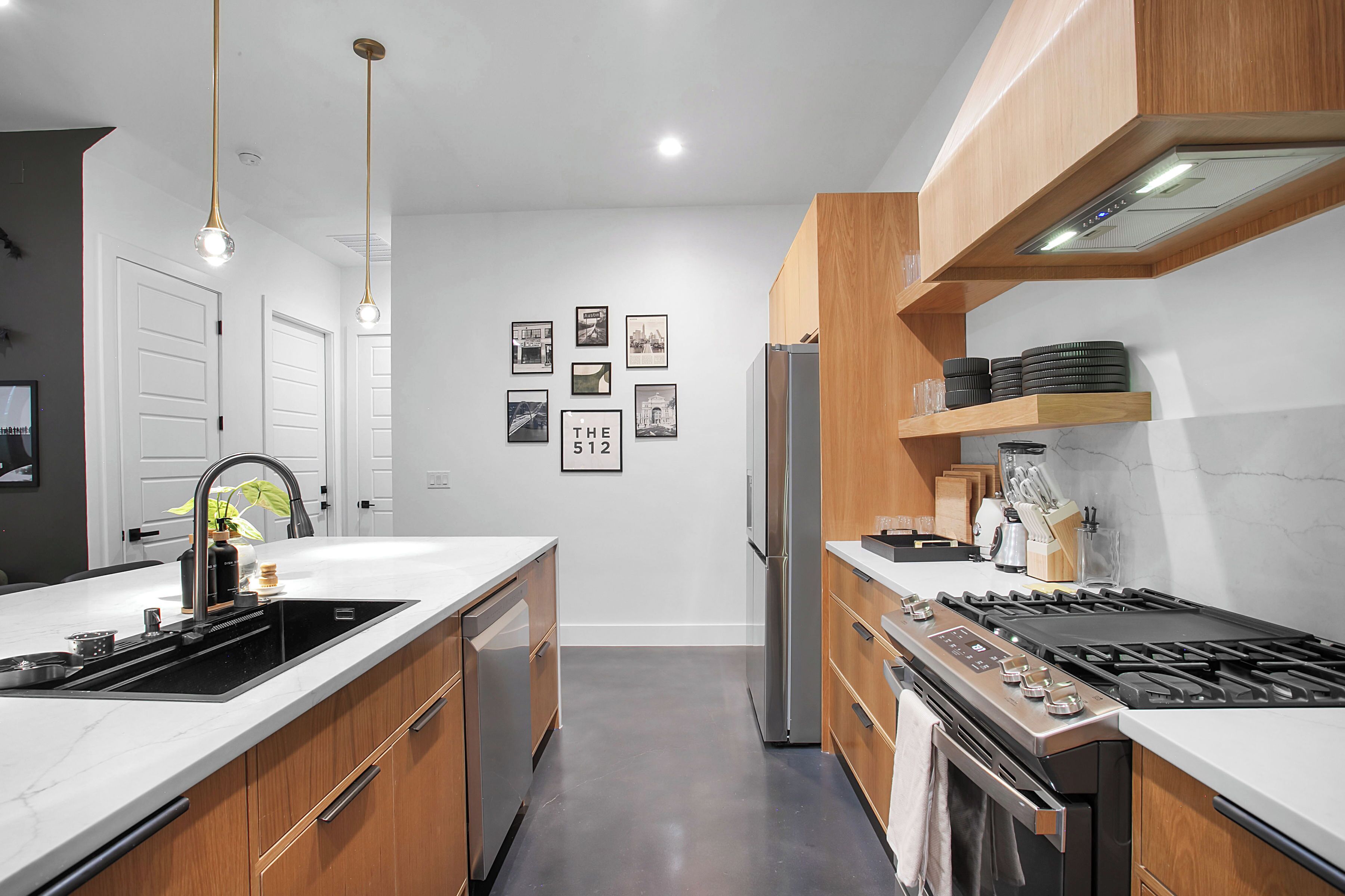 A modern kitchen with a central island, stainless steel appliances, wooden cabinets, and a marble backsplash.