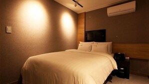 Ein Hotelzimmer mit einem Bett, einem Nachttisch und einer Klimaanlage.
