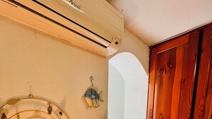 Een kamer met een houten deur, een wandairconditioner, een decoratieve vis, een spiraalvormige wanddecoratie en een tafel met een afstandsbediening.