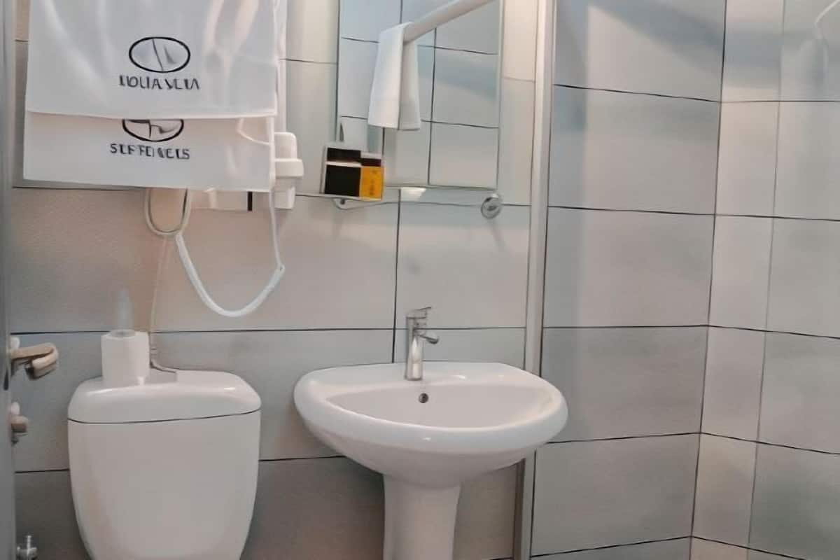 Une salle de bain avec des toilettes, un lavabo et une serviette accrochée au mur.