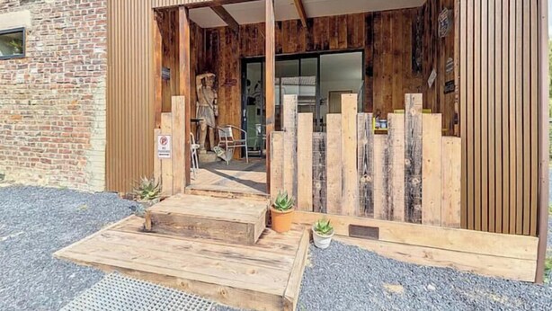 Un edificio moderno con fachada de madera y un acceso cubierto.
