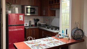 A kitchen with wooden cabinets, a red refrigerator, a microwave, a sink, and a clock on the wall. - Disegni 17 - Santiago Apartment, Close to Metro and Culture (Santiago)