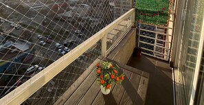 A balcony with a view of a street and a flower pot.
