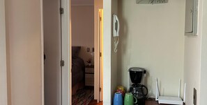 A small kitchenette with a coffee maker, mugs, and a Wi-Fi router.