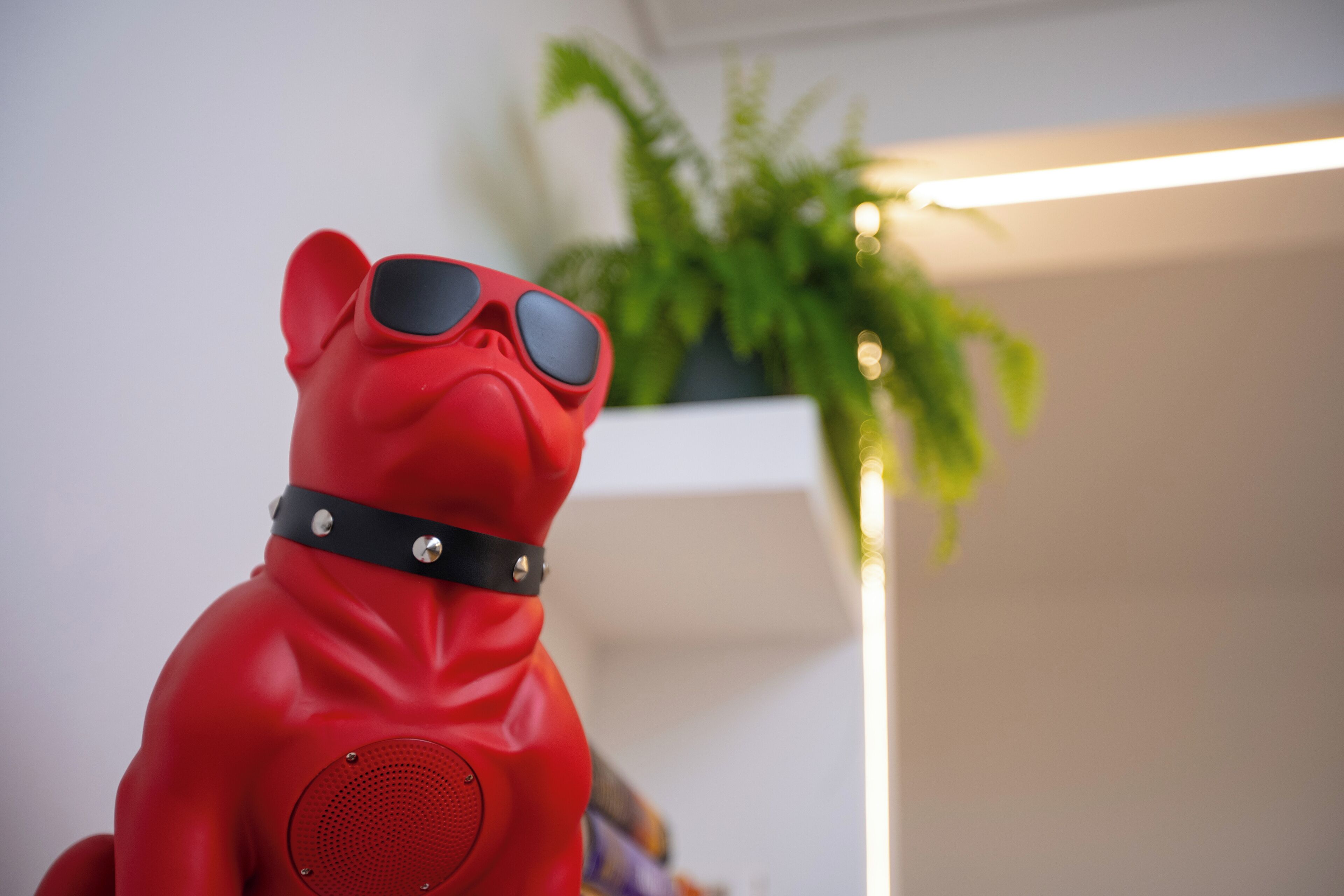 Uma estatueta de cachorro vermelho, com coleira preta e óculos de sol.