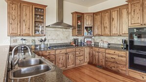 Una cocina con armarios de madera, encimeras de granito y electrodomésticos de acero inoxidable, incluyendo un horno empotrado.