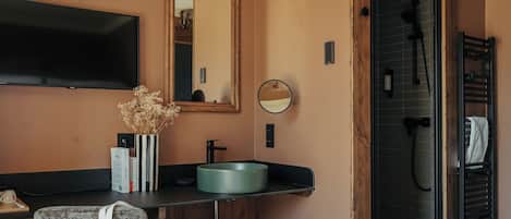 A modern bathroom with a wooden vanity, a round mirror, a built-in sink, and a shower area.