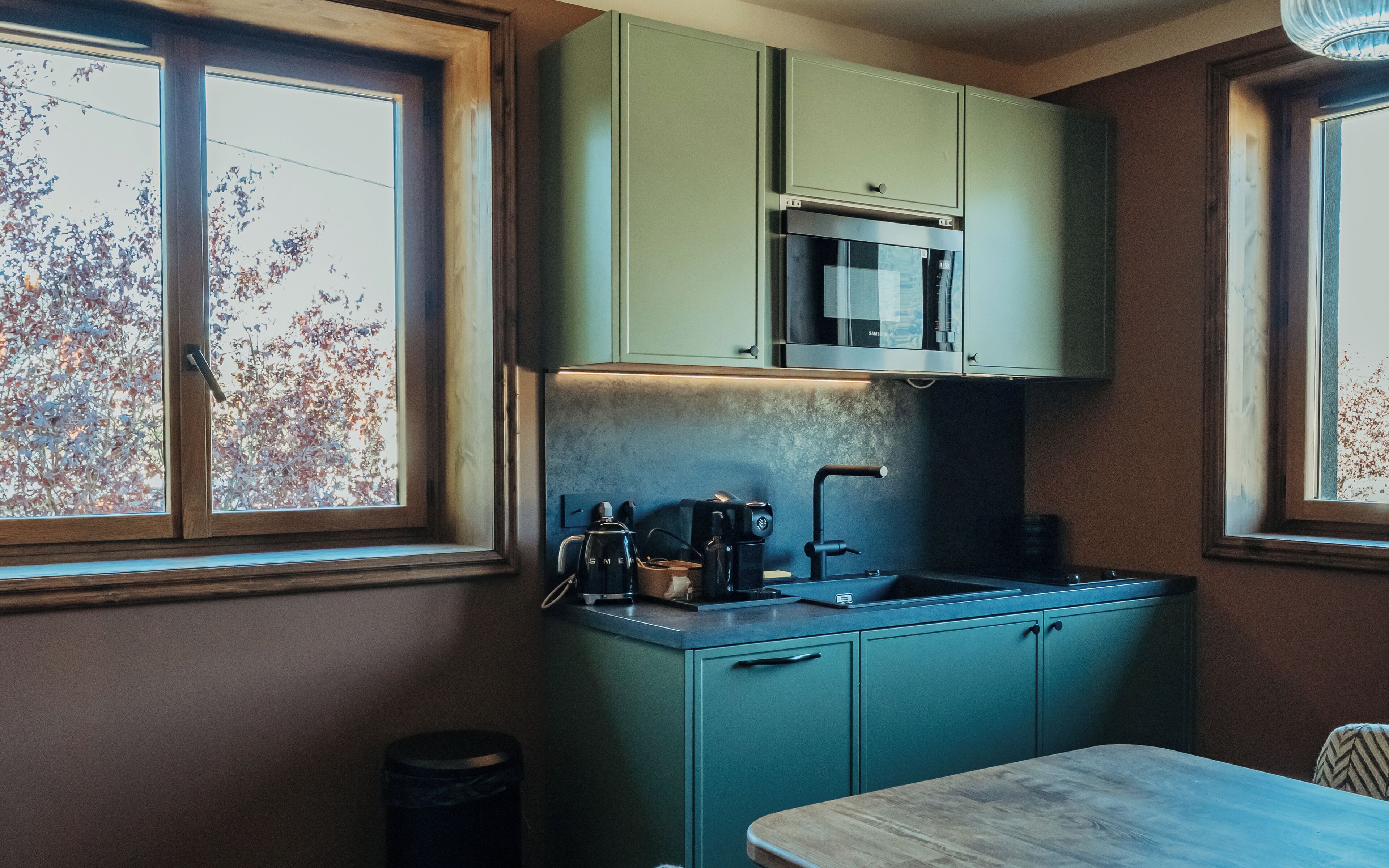 A compact kitchen with teal cabinets, a microwave, a coffee maker, and a sink.