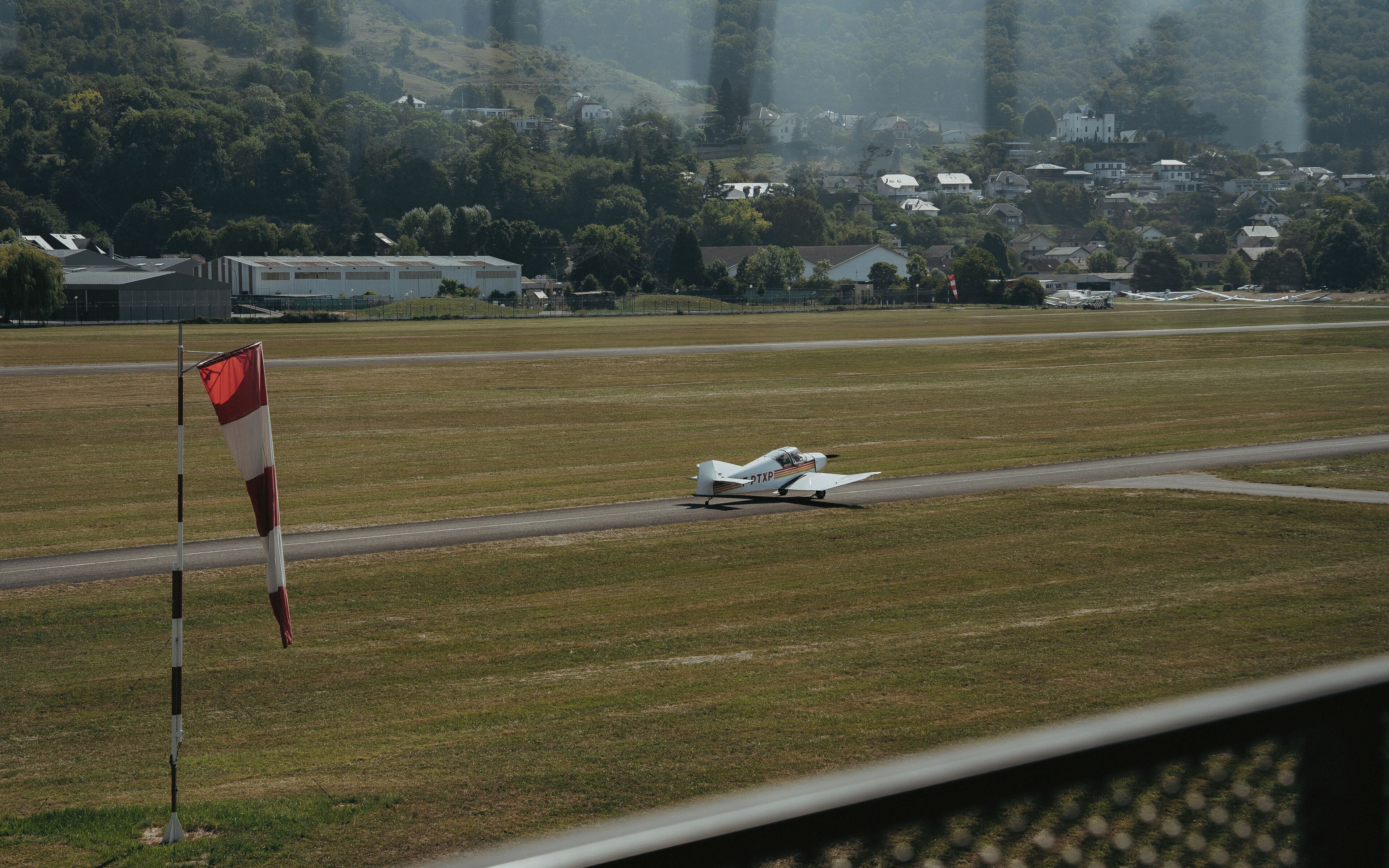 A small aircraft on a runway with a flag in the foreground.
