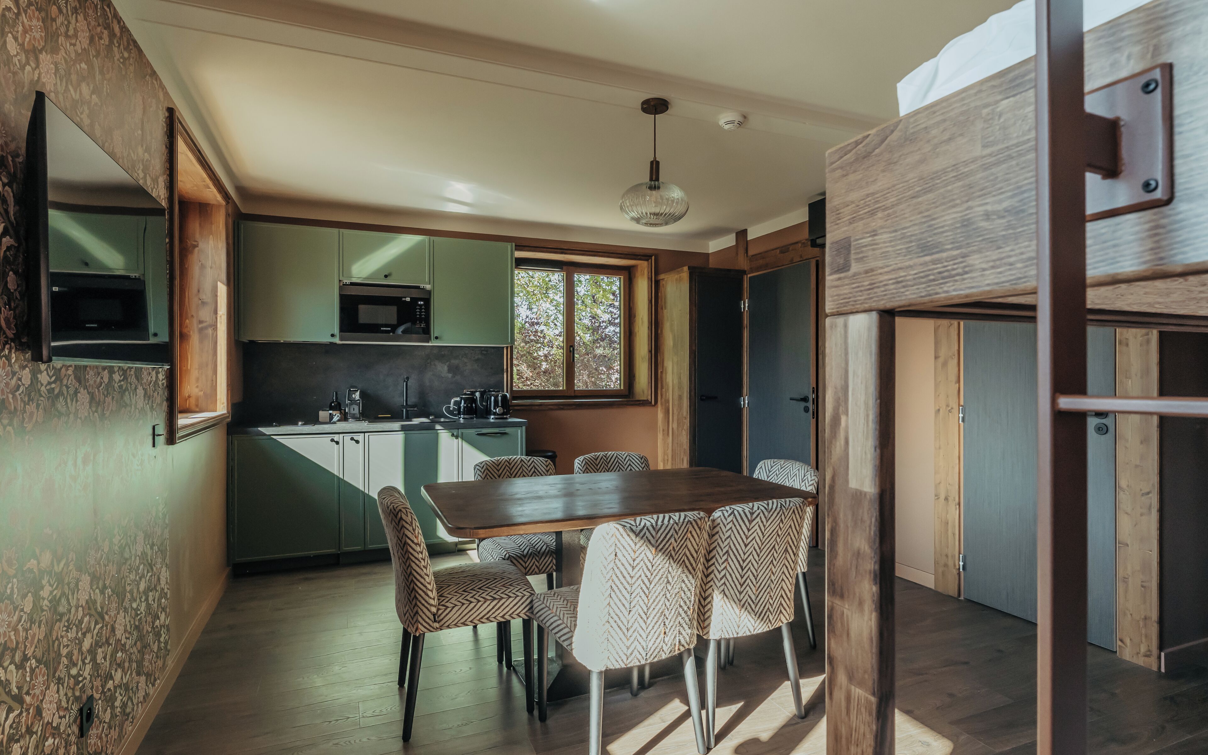 Cocina moderna con comedor, suelo de madera y vistas al exterior.