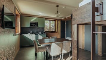Cocina moderna con comedor, suelo de madera y vistas al exterior.