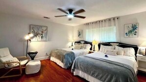 Un dormitorio con dos camas, ventilador de techo y obras de arte en las paredes.