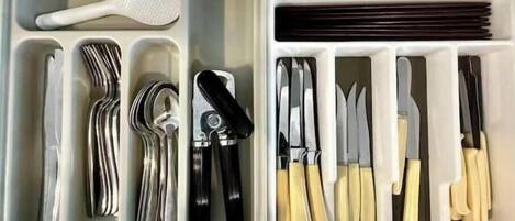 A drawer with utensils and cutlery organized in compartments.