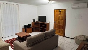 Un salon comprenant un canapé, une table basse, un téléviseur et un meuble en bois.