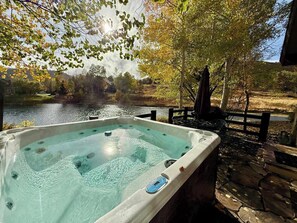 Uma banheira de hidromassagem com vista para um lago e árvores.