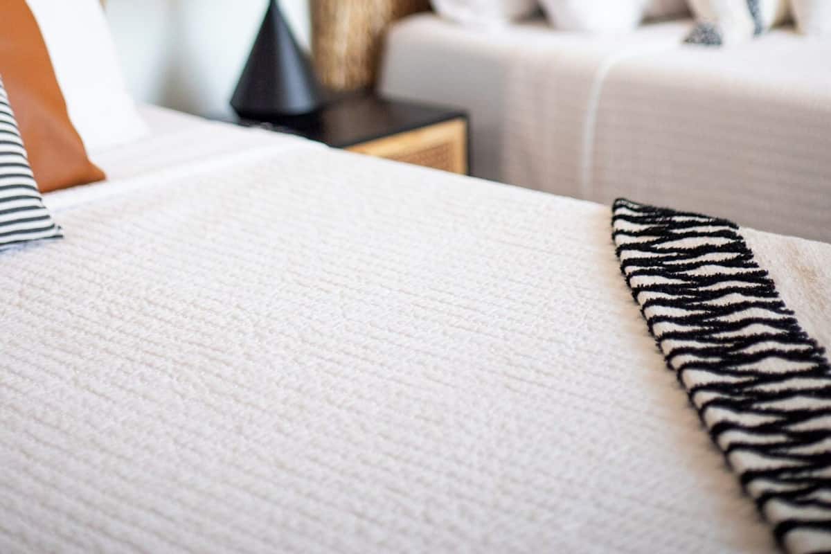 A hotel room with a bed, a nightstand, a lamp, and two framed pictures on the wall.