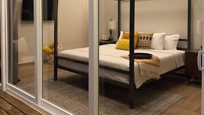A bedroom with a four-poster bed, a glass door, a ceiling fan, and a nightstand with a lamp. - The Bohemian Caye Caulker (Caye Caulker)