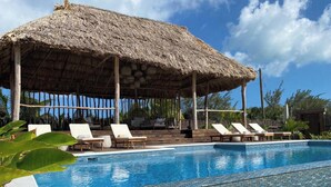 A pool area with lounge chairs and a thatched-roof structure. - The Bohemian Caye Caulker (Caye Caulker)
