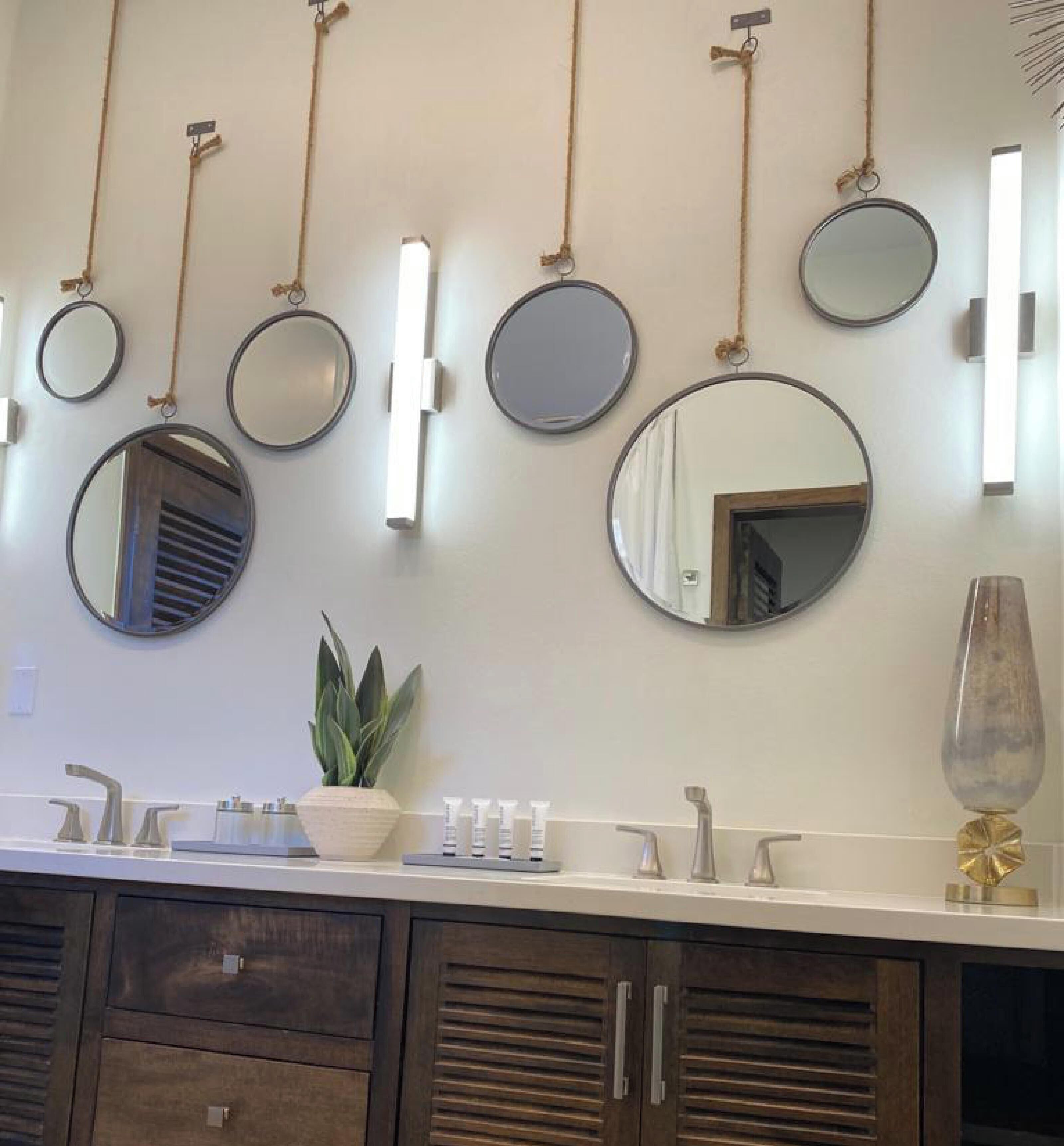A bathroom with multiple round mirrors, a potted plant, and a vase on the vanity.