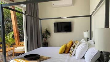 Un dormitorio con cama, televisor, lámpara y vistas al exterior.