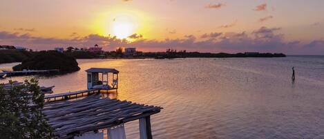 A waterfront view with a gazebo, calm water, and distant buildings.