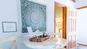 Un rincón de comedor con una mesa redonda, dos sillas y un adorno en la pared.