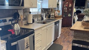 A modern kitchen with white cabinetry, stainless steel appliances, and a wooden floor.