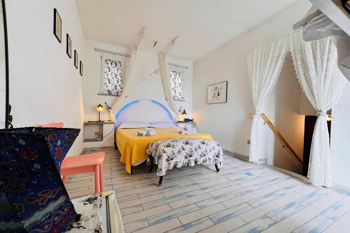 Un dormitorio con cama, mesitas de noche, una silla y una escalera.