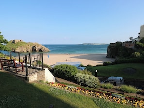 Une vue sur la côte, avec une plage, un drapeau, un banc et un jardin fleuri.