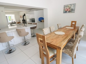 Une cuisine moderne avec des meubles blancs, une table à manger en bois et des tabourets de bar.