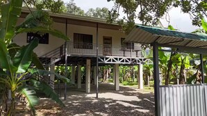A two-story building with a balcony, surrounded by tropical vegetation. - Cool Comfort & Local Charm (Savegre de Aguirre)