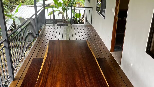 A wooden deck with a table and benches, surrounded by a railing and large windows. - Cool Comfort & Local Charm (Savegre de Aguirre)
