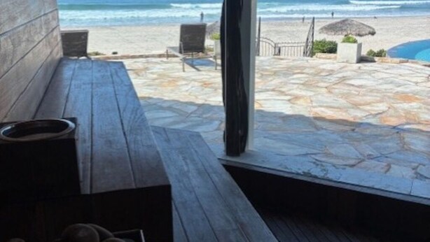 A wooden deck with a stone floor leading to a beach view.