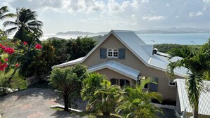 A house with a sloped roof, a small porch, and a view of the sea. - Villa panoramic sea view & private pool (Le Robert)