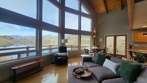 Ein großzügiges Wohnzimmer mit großen Fenstern, einem gemütlichen Sofa, einem Holztisch und einem Essbereich.