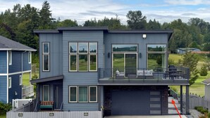 Una moderna casa a due piani con garage, ampie finestre e un balcone.