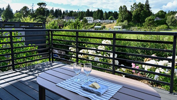 Un terrazza in legno con tavolo, due bicchieri e un tagliere di formaggi.